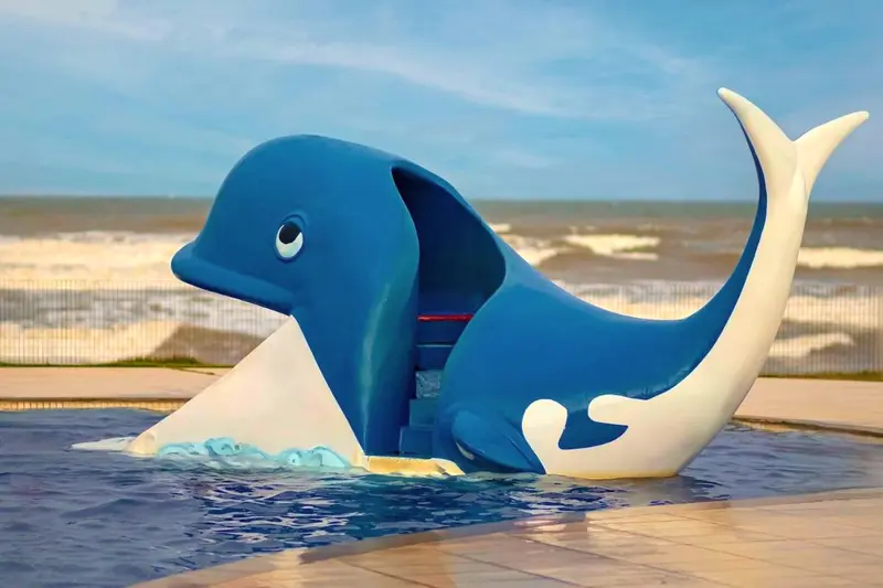 Escorregador em forma de baleia azul na piscina infantil, com o mar ao fundo