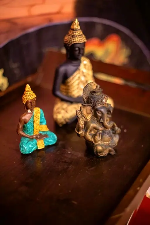 Três pequenas estátuas de Buda sobre uma mesa escura, com luz suave