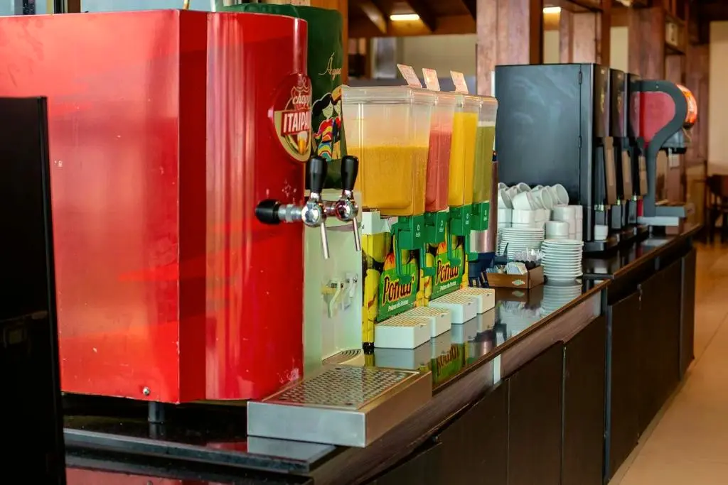 Linha de dispensadores de sucos, chopeira vermelha e máquinas de café