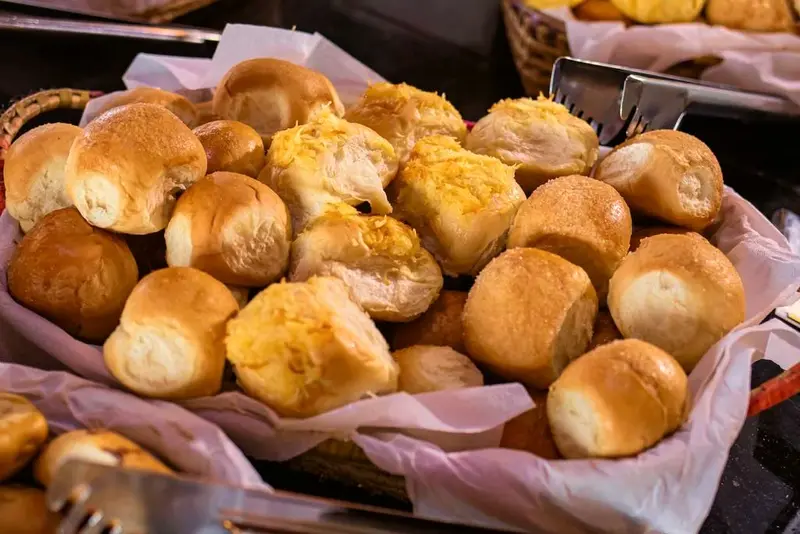Cesta de pãezinhos dourados com queijo no bufê
