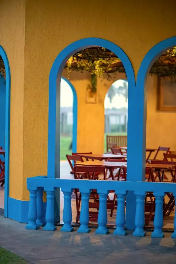 Pátio com arcos azuis, mesas e cadeiras de madeira