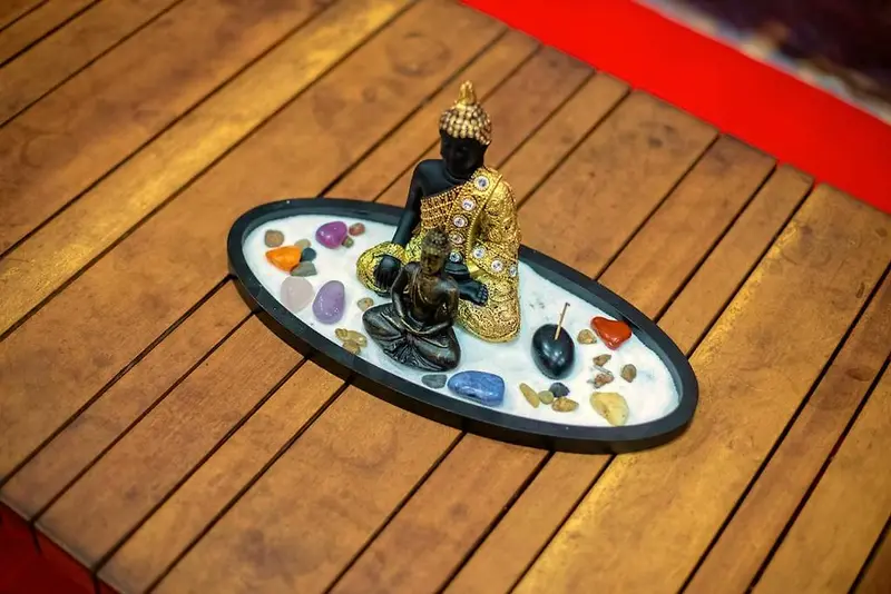 Pequena estátua de Buda cercada por pedras coloridas sobre o deck de madeira