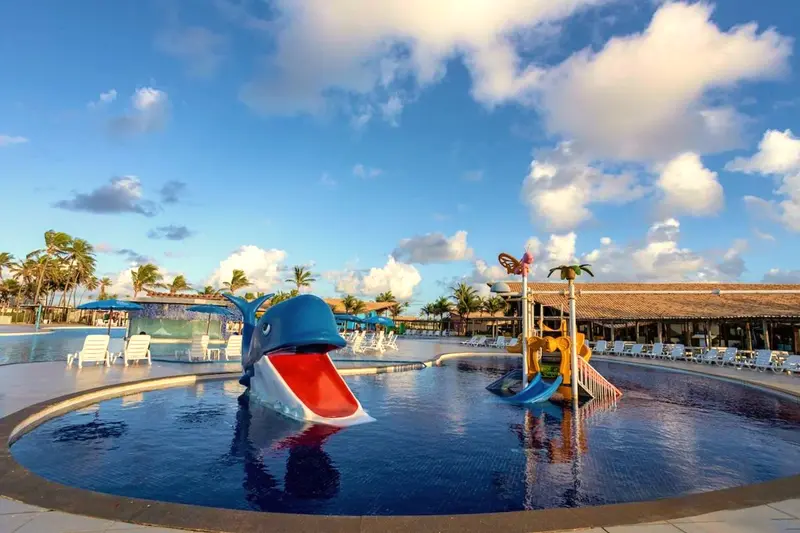 Piscina infantil com escorregador de baleia e playground aquático sob o céu azul