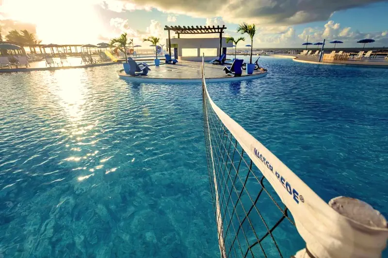 Rede de vôlei esticada dentro da piscina, com o bar e o pergolado ao fundo