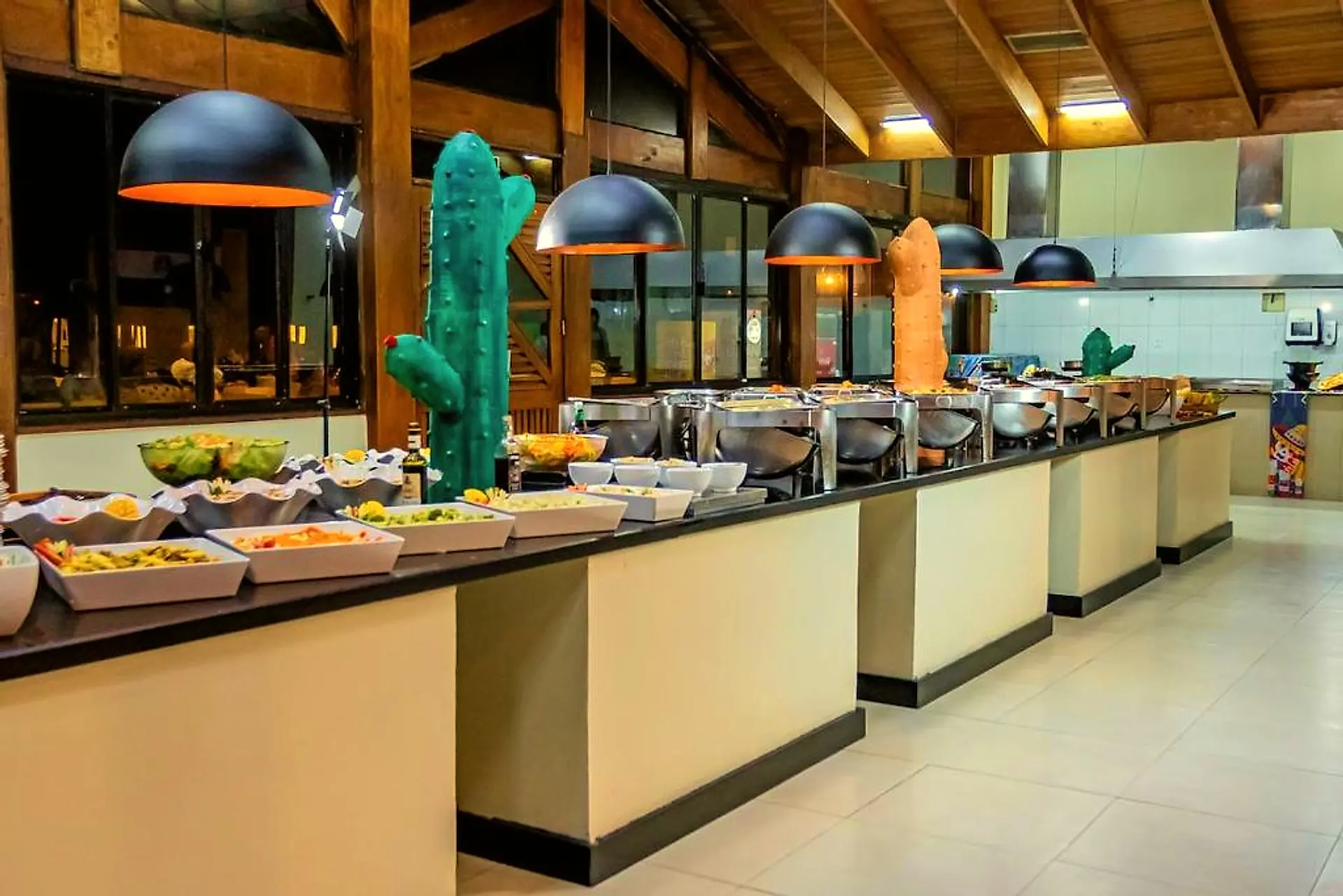 Salão do bufê com bancadas de cubas, cacto decorativo e teto de madeira
