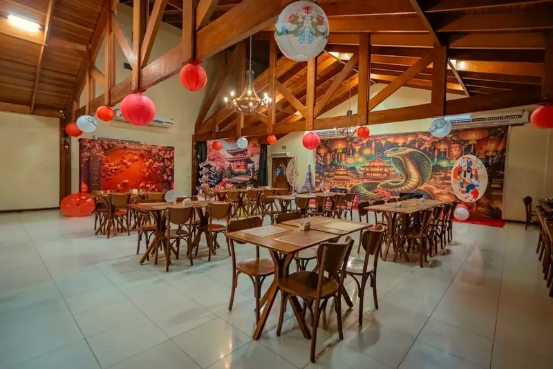 Salão do restaurante com mesas de madeira e decoração oriental com lanternas vermelhas