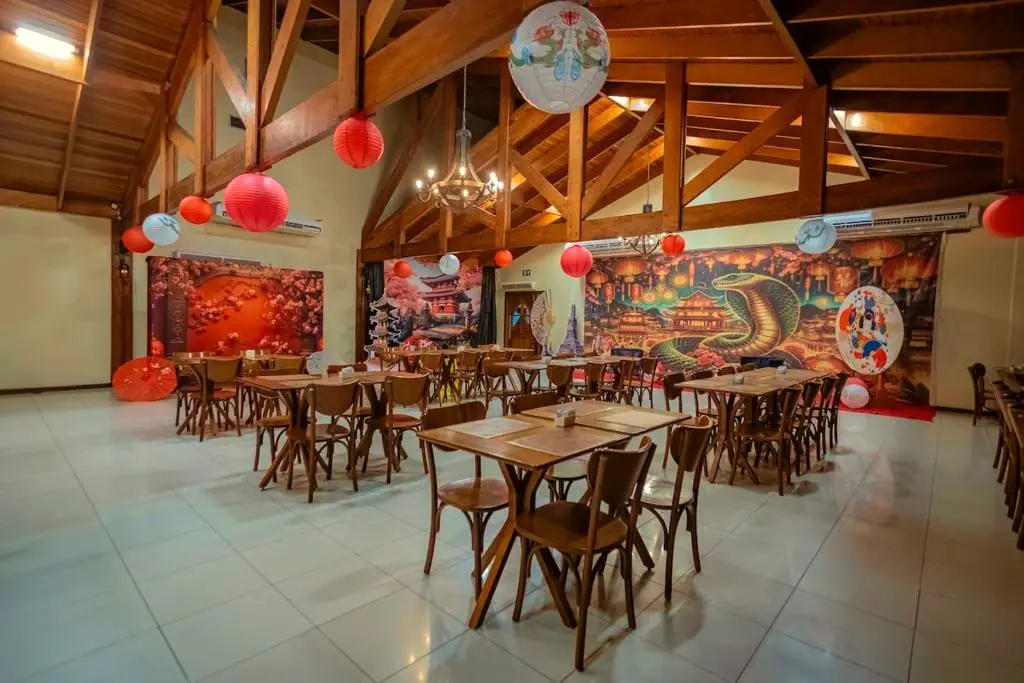 Salão do restaurante com mesas de madeira e decoração oriental com lanternas vermelhas