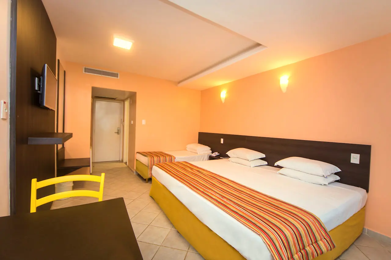 Apartamento Superior Vista Mar com cama de casal, cadeira amarela e cama de solteiro